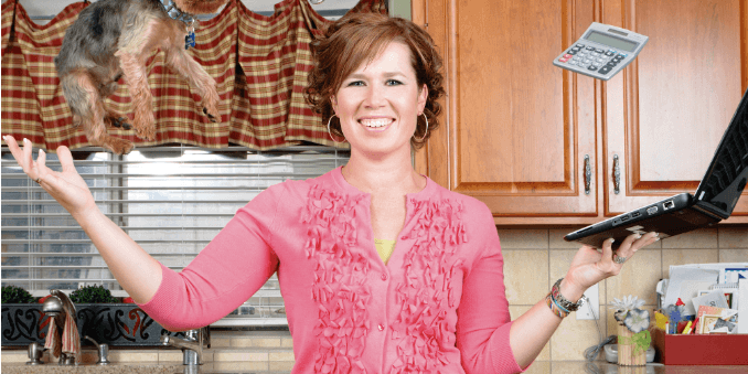 A woman in a pink cardigan smiles while juggling a frying pan, a laptop, and a small dog in a lively kitchen, illustrating the challenges of multitasking and the importance of effective campaign strategies.