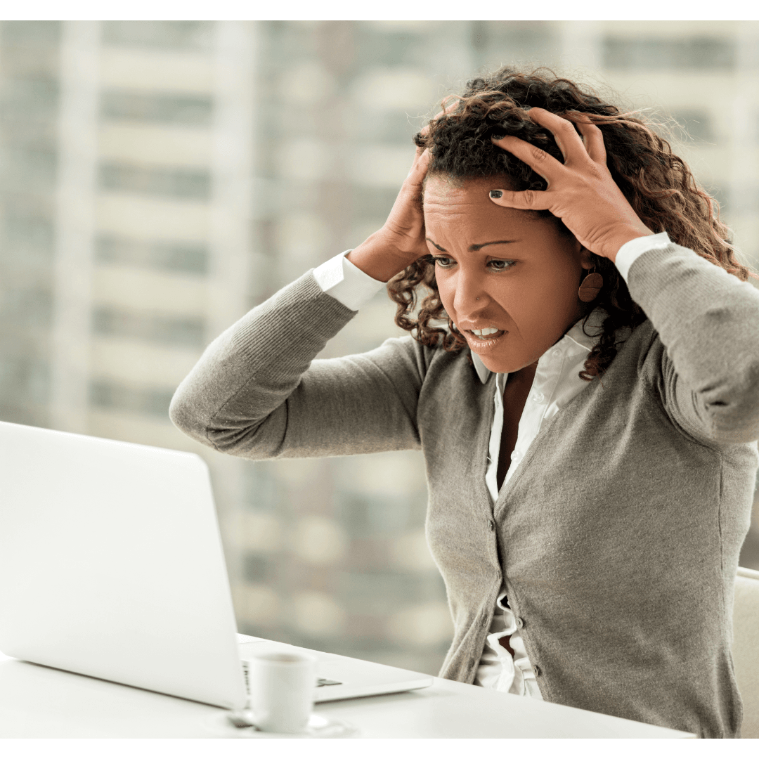 A frustrated woman with curly hair, clutching her head in stress while looking at a laptop, representing the challenges of work and the need for effective campaign metrics.