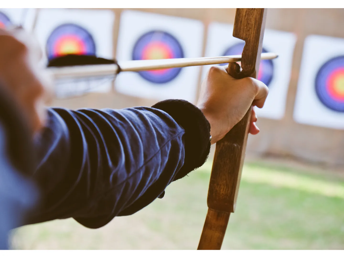 A person drawing a bow and preparing to shoot an arrow towards archery targets in the background, symbolizing focus and precision in targeting the right pricing strategy.