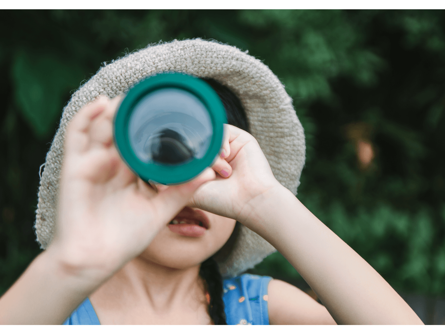 Close-up of a child holding a green telescope, peering through it with a focused look, symbolizing the act of discovering hidden insights and trends.